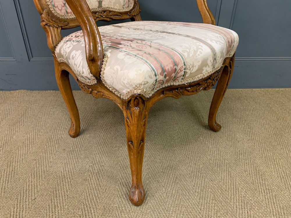 A pair of French carved walnut armchairs featuring cabriole legs and pink and cream patterned fabric upholstery. View XIV