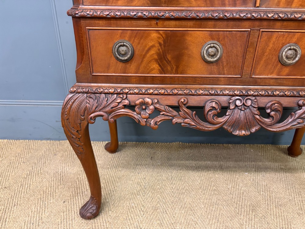 An antique Queen Anne style glazed display cabinet in warm brown wood featuring arched doors with glass panes, drawers with brass handles, and carved cabriole legs. View VII
