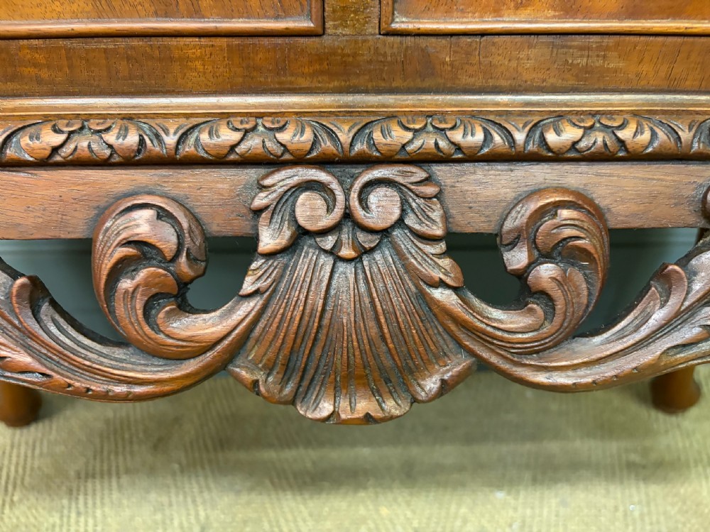 An antique Queen Anne style glazed display cabinet in warm brown wood featuring arched doors with glass panes, drawers with brass handles, and carved cabriole legs. View VIII