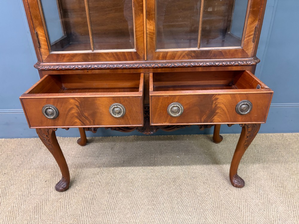 An antique Queen Anne style glazed display cabinet in warm brown wood featuring arched doors with glass panes, drawers with brass handles, and carved cabriole legs. View XIII