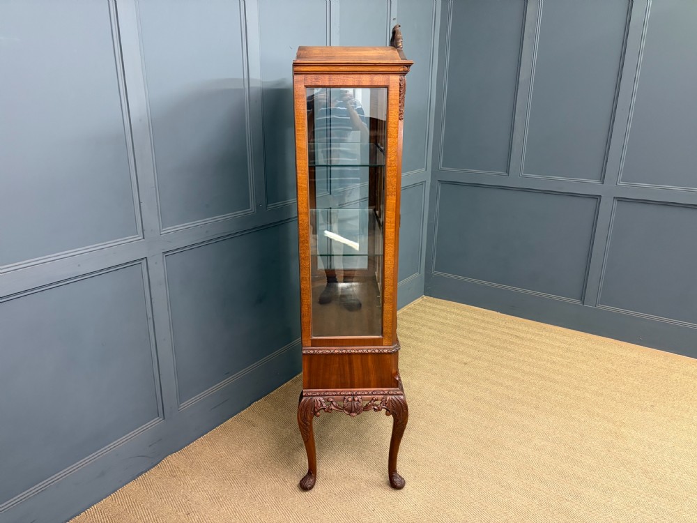 An antique Queen Anne style glazed display cabinet in warm brown wood featuring arched doors with glass panes, drawers with brass handles, and carved cabriole legs. View XVI