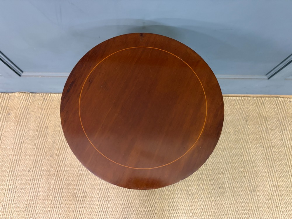 An Edwardian mahogany wine table featuring a circular top with satinwood inlay, a turned central column, and a tripod base. View IV