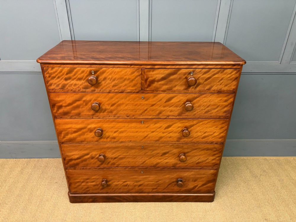 A Victorian chest of drawers in warm brown figured timber featuring turned handles and a plinth base. View III
