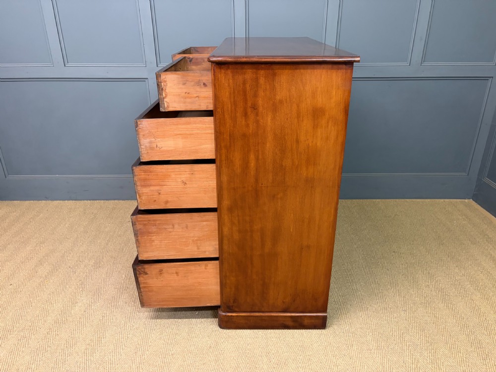A Victorian chest of drawers in warm brown figured timber featuring turned handles and a plinth base. View XIV