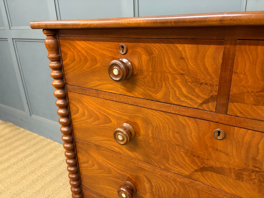 A Victorian flame mahogany chest of drawers featuring two short over three long drawers flanked by spiral turned columns resting on a solid plinth base. View V