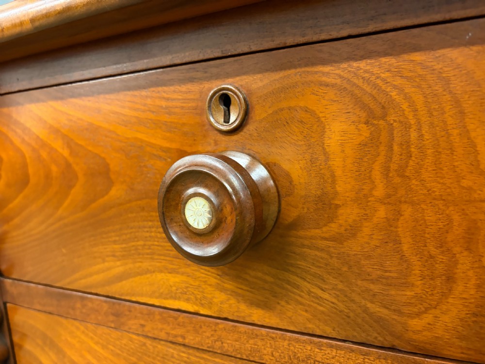 A Victorian flame mahogany chest of drawers featuring two short over three long drawers flanked by spiral turned columns resting on a solid plinth base. View VI