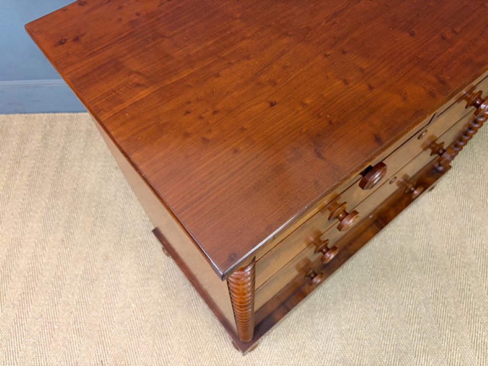 A Victorian flame mahogany chest of drawers featuring two short over three long drawers flanked by spiral turned columns resting on a solid plinth base. View XI