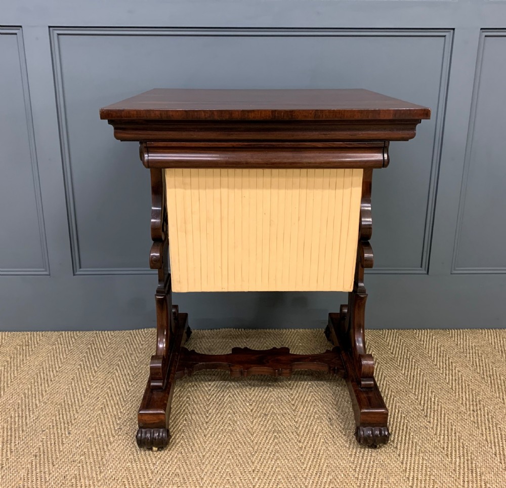 A William IV rosewood work table featuring a square top above a pleated cream fabric basket supported by carved scroll legs. View III