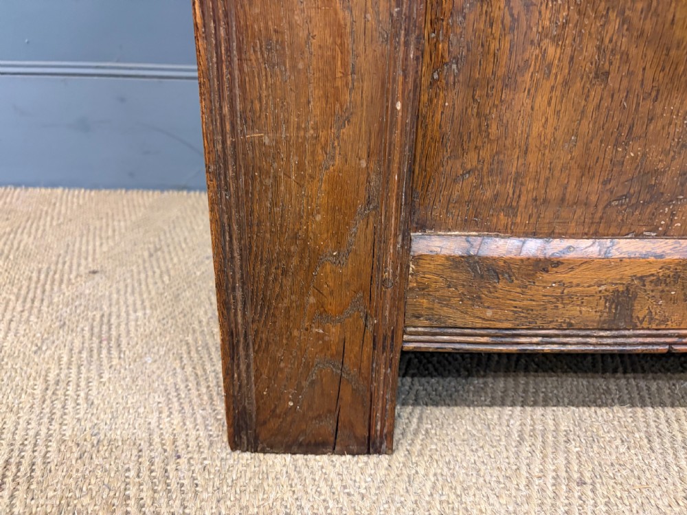 A Georgian oak coffer featuring a three-panel front framing, a hinged top, and a brass keyhole escutcheon. View V