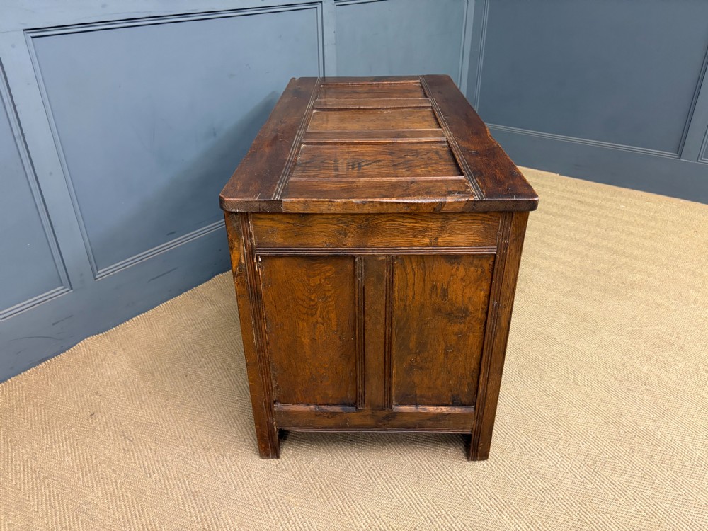 A Georgian oak coffer featuring a three-panel front framing, a hinged top, and a brass keyhole escutcheon. View XI