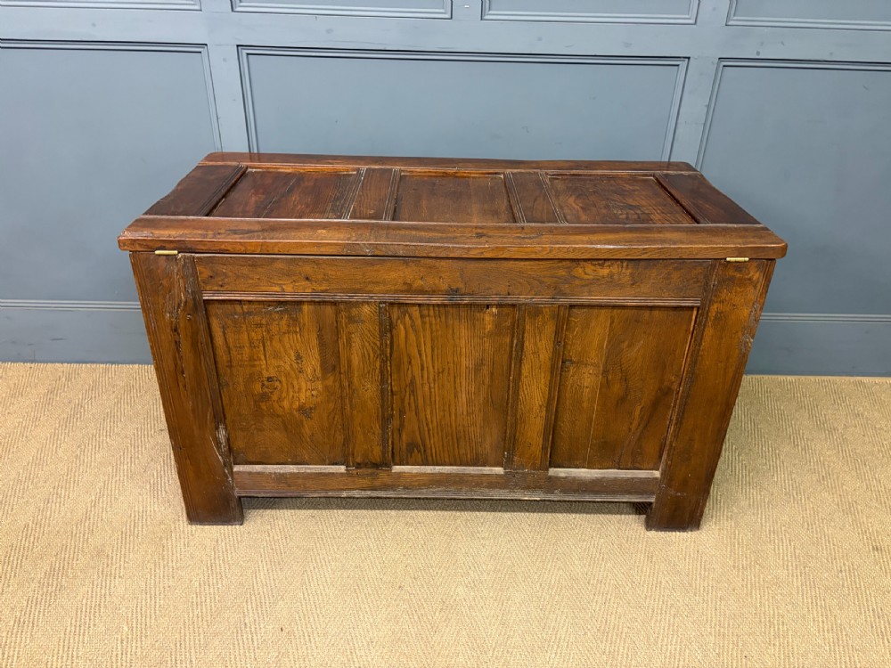 A Georgian oak coffer featuring a three-panel front framing, a hinged top, and a brass keyhole escutcheon. View XV