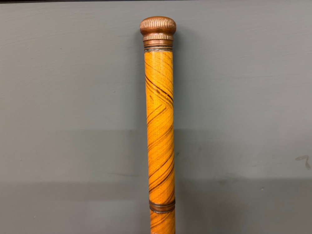 A Victorian wooden walking cane featuring a spiral pattern along the tapered shaft and a metal collar. View II