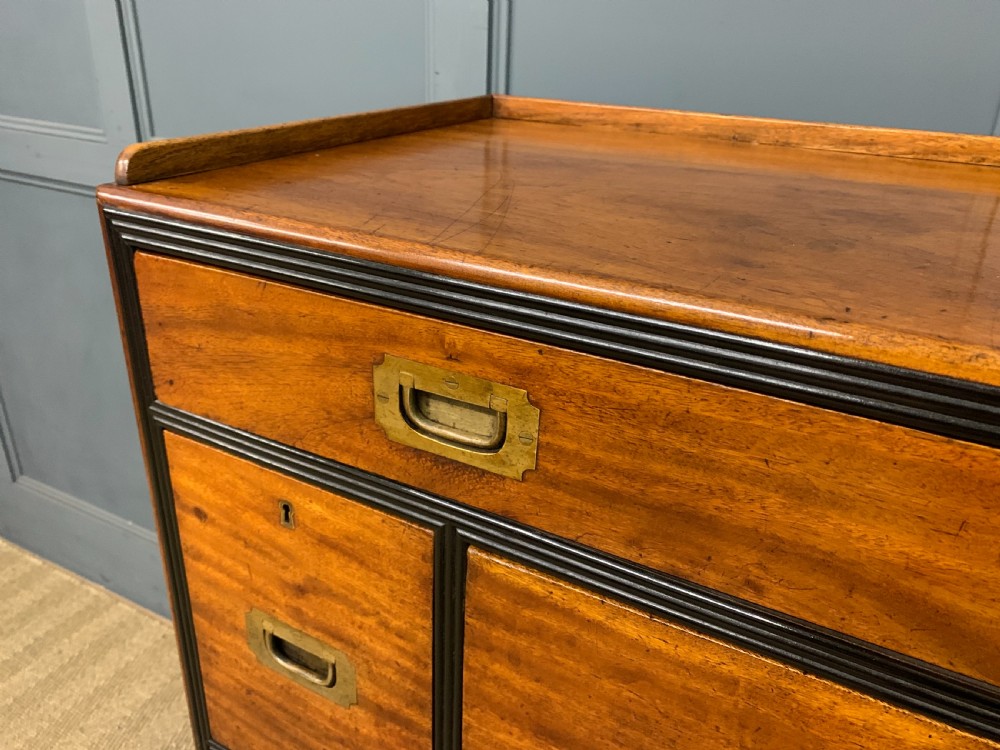 A nineteenth-century camphor wood military campaign chest with dark wood borders, flush brass handles, and a central drop-front secretaire section. View IV