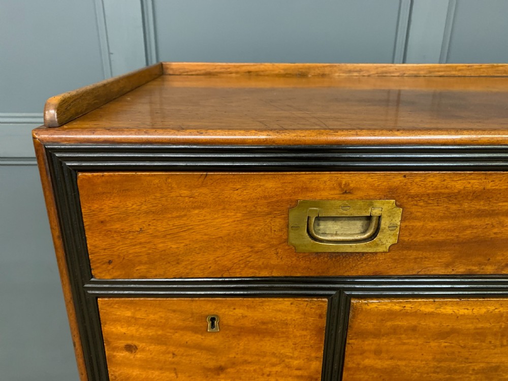 A nineteenth-century camphor wood military campaign chest with dark wood borders, flush brass handles, and a central drop-front secretaire section. View V