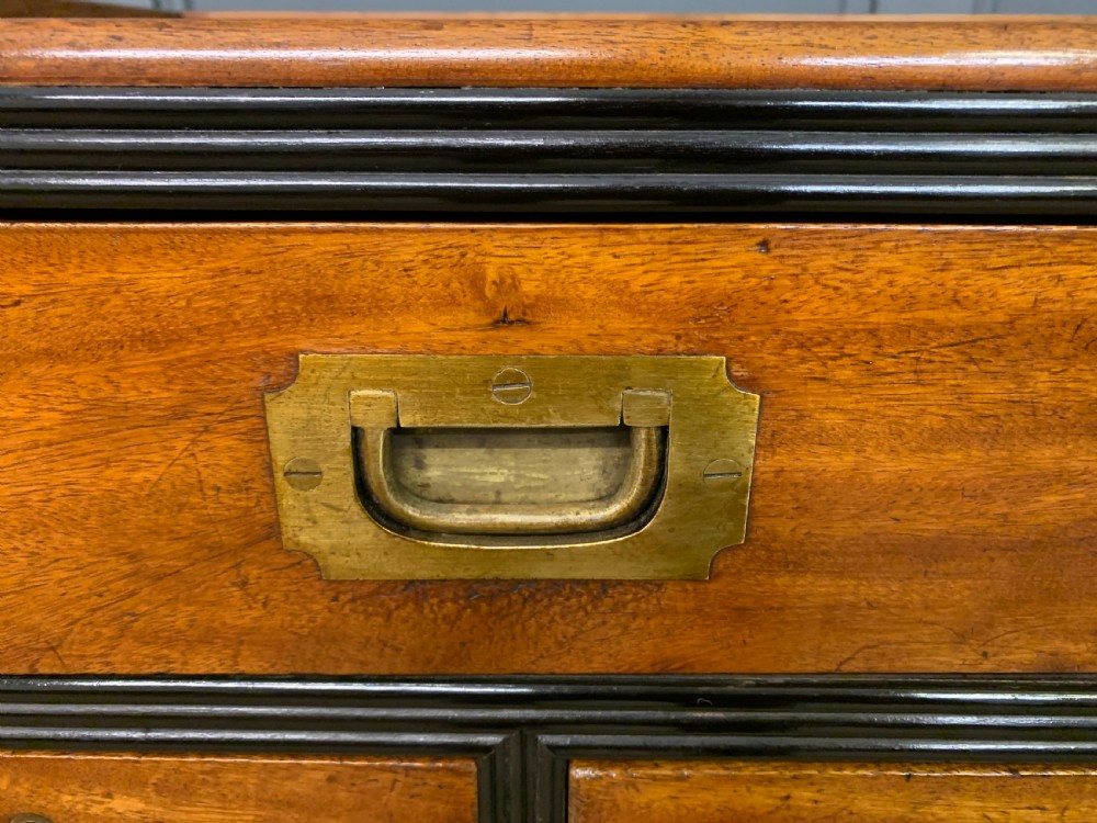 A nineteenth-century camphor wood military campaign chest with dark wood borders, flush brass handles, and a central drop-front secretaire section. View VI
