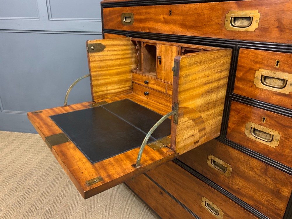A nineteenth-century camphor wood military campaign chest with dark wood borders, flush brass handles, and a central drop-front secretaire section. View XVII