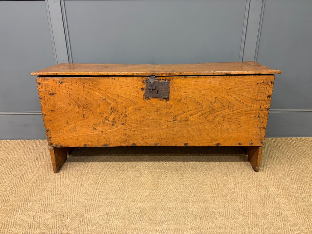 An 18th-century elm coffer featuring a rectangular hinged lid, prominent wood grain, central iron lockplate, and slab ends. View II