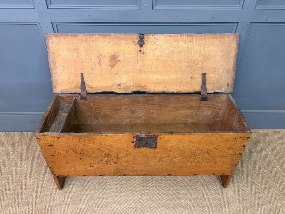 An 18th-century elm coffer featuring a rectangular hinged lid, prominent wood grain, central iron lockplate, and slab ends. View IV