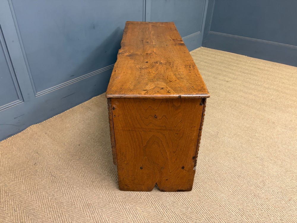 An 18th-century elm coffer featuring a rectangular hinged lid, prominent wood grain, central iron lockplate, and slab ends. View VIII
