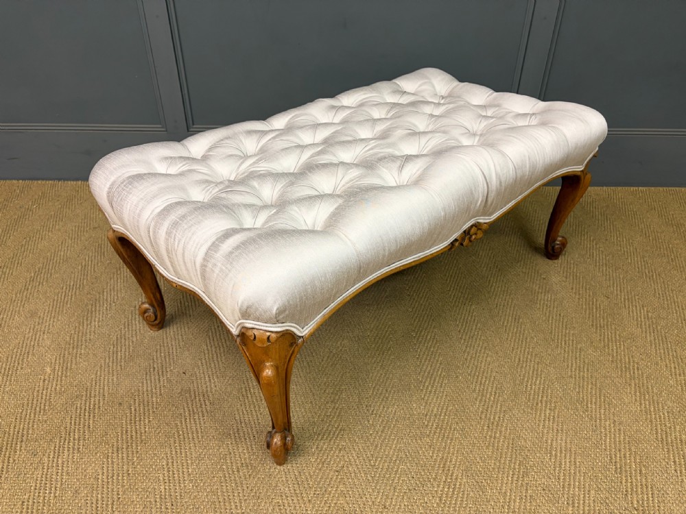 A large rectangular Victorian rosewood stool with deep-buttoned cream upholstery and carved cabriole legs.