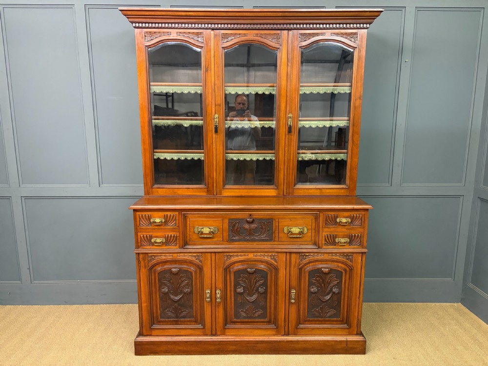 A large Victorian walnut secretaire bookcase featuring three upper glazed doors with arched panels over a central carved writing drawer and lower carved cupboard doors. View III