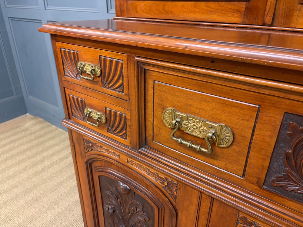A large Victorian walnut secretaire bookcase featuring three upper glazed doors with arched panels over a central carved writing drawer and lower carved cupboard doors. View V