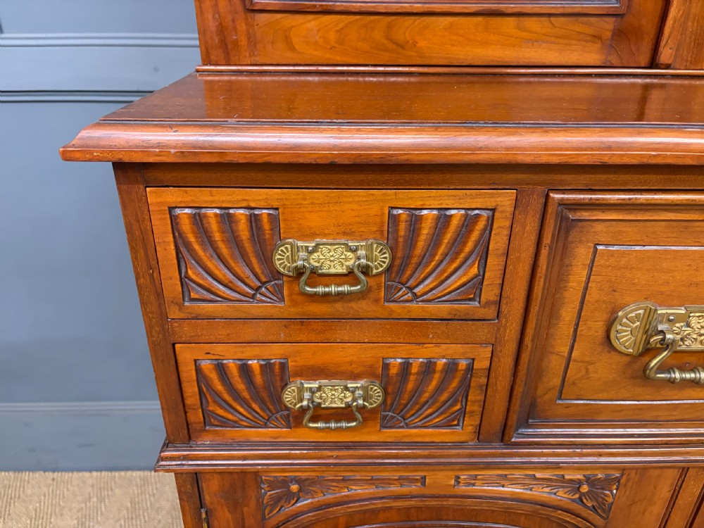 A large Victorian walnut secretaire bookcase featuring three upper glazed doors with arched panels over a central carved writing drawer and lower carved cupboard doors. View VI