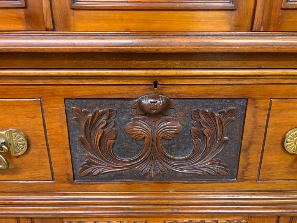 A large Victorian walnut secretaire bookcase featuring three upper glazed doors with arched panels over a central carved writing drawer and lower carved cupboard doors. View XVII