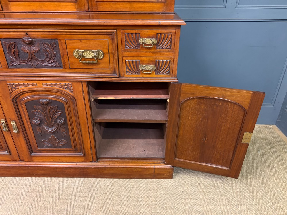 A large Victorian walnut secretaire bookcase featuring three upper glazed doors with arched panels over a central carved writing drawer and lower carved cupboard doors. View XXVI