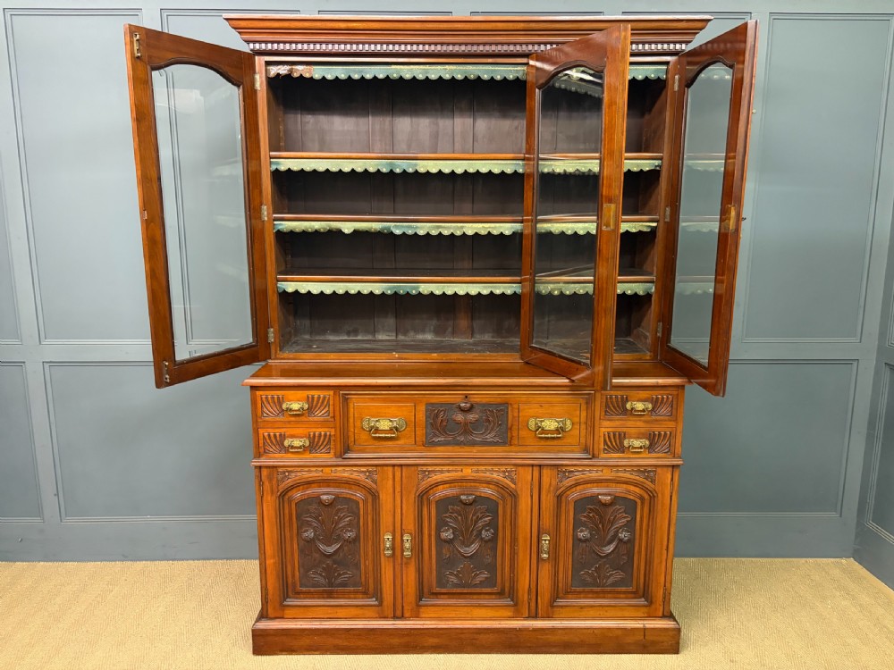A large Victorian walnut secretaire bookcase featuring three upper glazed doors with arched panels over a central carved writing drawer and lower carved cupboard doors. View XXVII