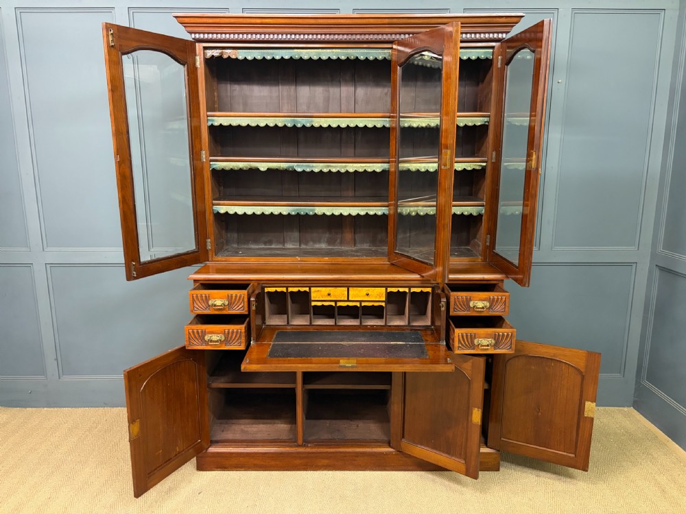 A large Victorian walnut secretaire bookcase featuring three upper glazed doors with arched panels over a central carved writing drawer and lower carved cupboard doors. View XXVIII