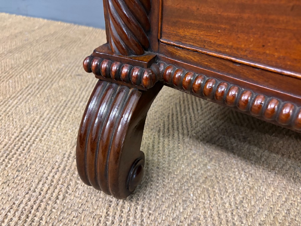 A Regency period mahogany bowfront chest of drawers featuring four graduated drawers, reeded side columns, brass ring handles, and turned feet. View X