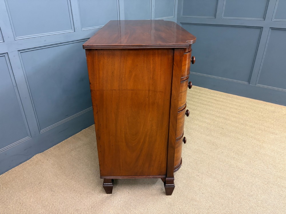 A George IV flame mahogany chest of drawers featuring a bowfront profile, turned wooden handles, and carved side columns. View XIII