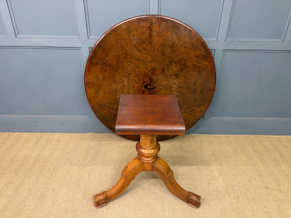 A circular burr walnut centre table featuring a quartered figured veneer top over a turned central pedestal with four carved scroll legs. View V