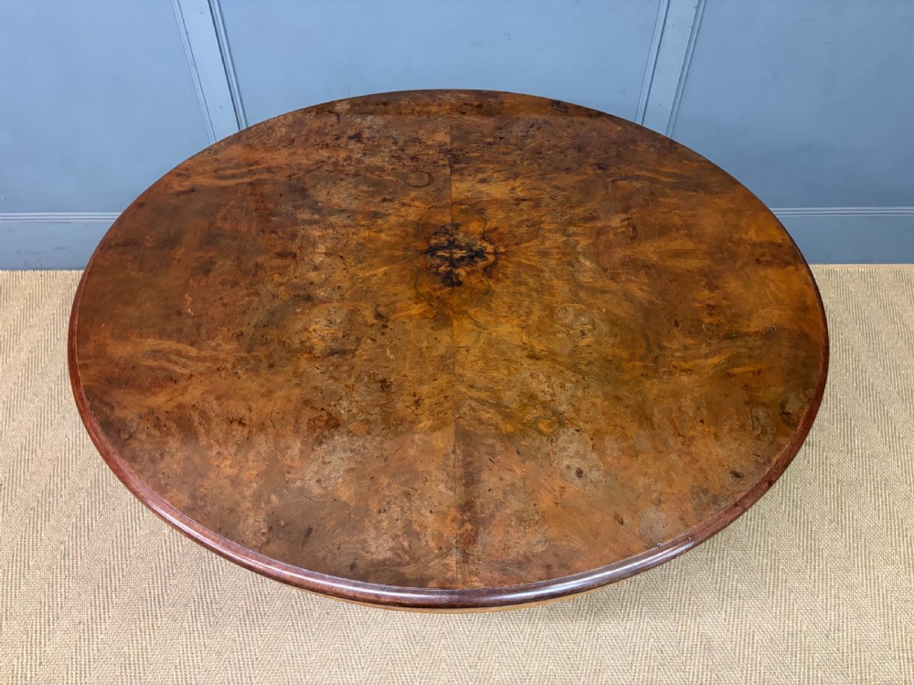 A circular burr walnut centre table featuring a quartered figured veneer top over a turned central pedestal with four carved scroll legs. View VIII