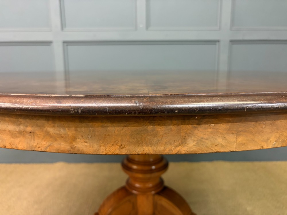 A circular burr walnut centre table featuring a quartered figured veneer top over a turned central pedestal with four carved scroll legs. View IX
