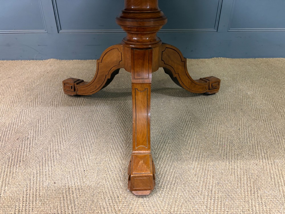 A circular burr walnut centre table featuring a quartered figured veneer top over a turned central pedestal with four carved scroll legs. View XIII