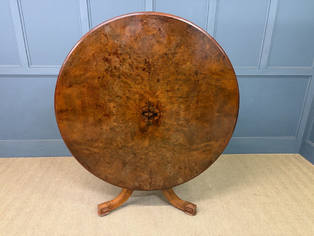 A circular burr walnut centre table featuring a quartered figured veneer top over a turned central pedestal with four carved scroll legs. View XIV