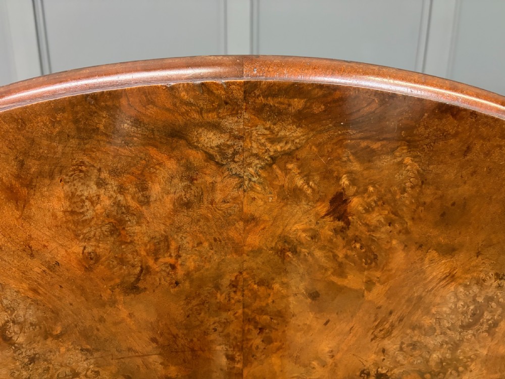 A circular burr walnut centre table featuring a quartered figured veneer top over a turned central pedestal with four carved scroll legs. View XVI