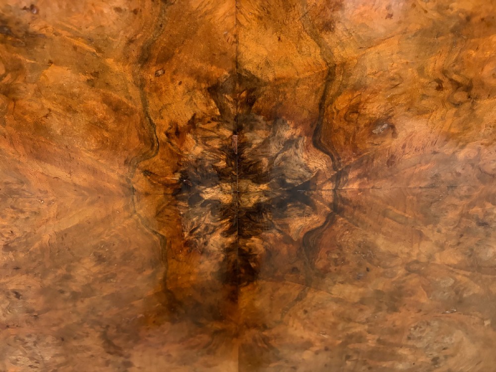 A circular burr walnut centre table featuring a quartered figured veneer top over a turned central pedestal with four carved scroll legs. View XVII
