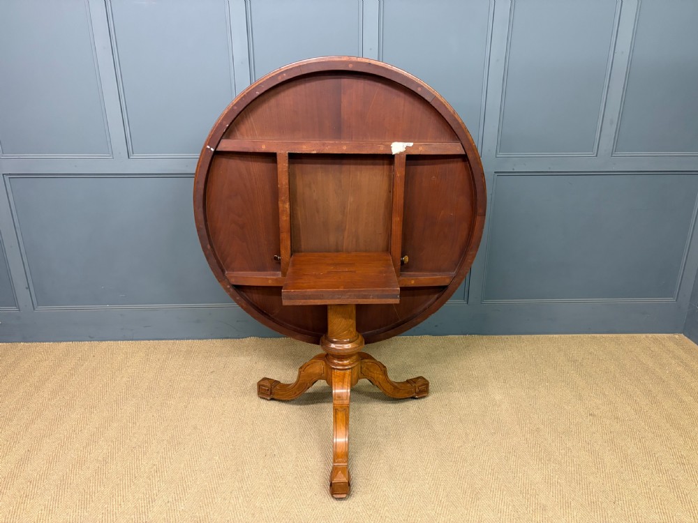 A circular burr walnut centre table featuring a quartered figured veneer top over a turned central pedestal with four carved scroll legs. View XIX