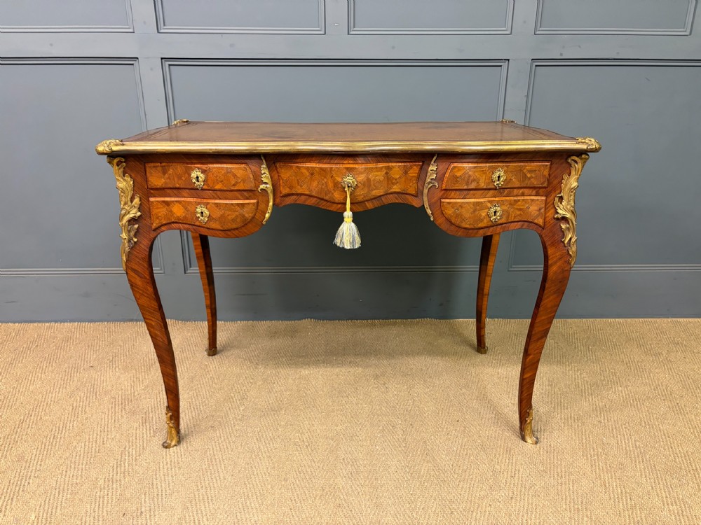 A 19th-century French Louis XV style writing desk with geometric parquetry veneers, gilt-bronze mounts, cabriole legs, and a warm brown leather writing surface. View III