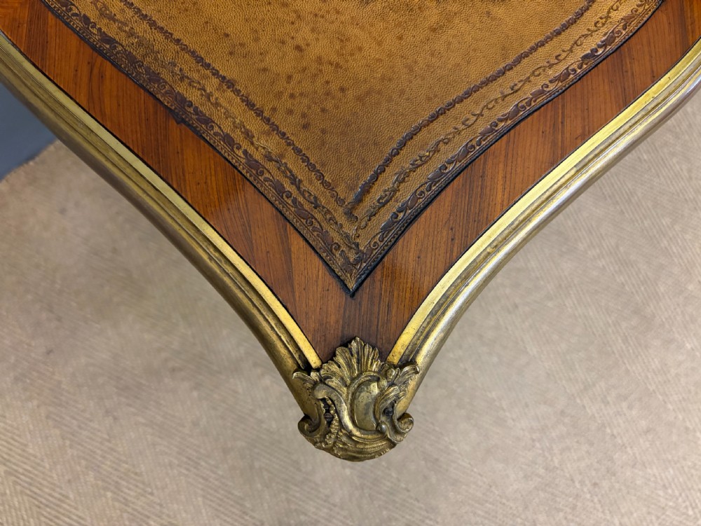 A 19th-century French Louis XV style writing desk with geometric parquetry veneers, gilt-bronze mounts, cabriole legs, and a warm brown leather writing surface. View V