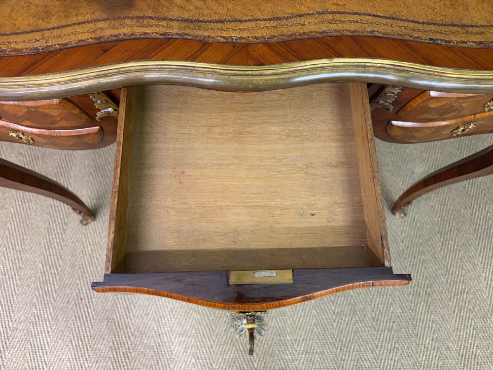 A 19th-century French Louis XV style writing desk with geometric parquetry veneers, gilt-bronze mounts, cabriole legs, and a warm brown leather writing surface. View XIII