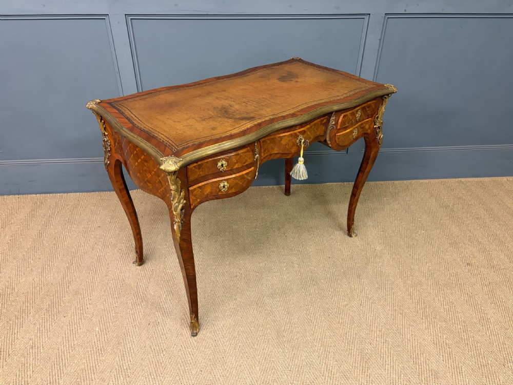 A 19th-century French Louis XV style writing desk with geometric parquetry veneers, gilt-bronze mounts, cabriole legs, and a warm brown leather writing surface. View XIV