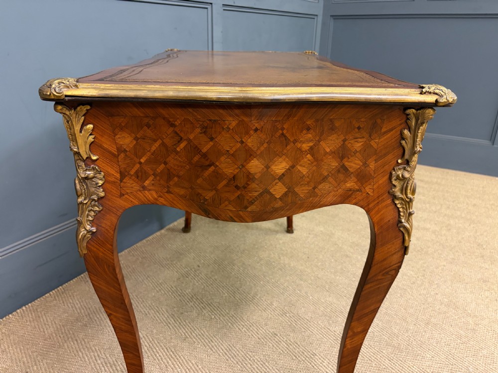A 19th-century French Louis XV style writing desk with geometric parquetry veneers, gilt-bronze mounts, cabriole legs, and a warm brown leather writing surface. View XVI