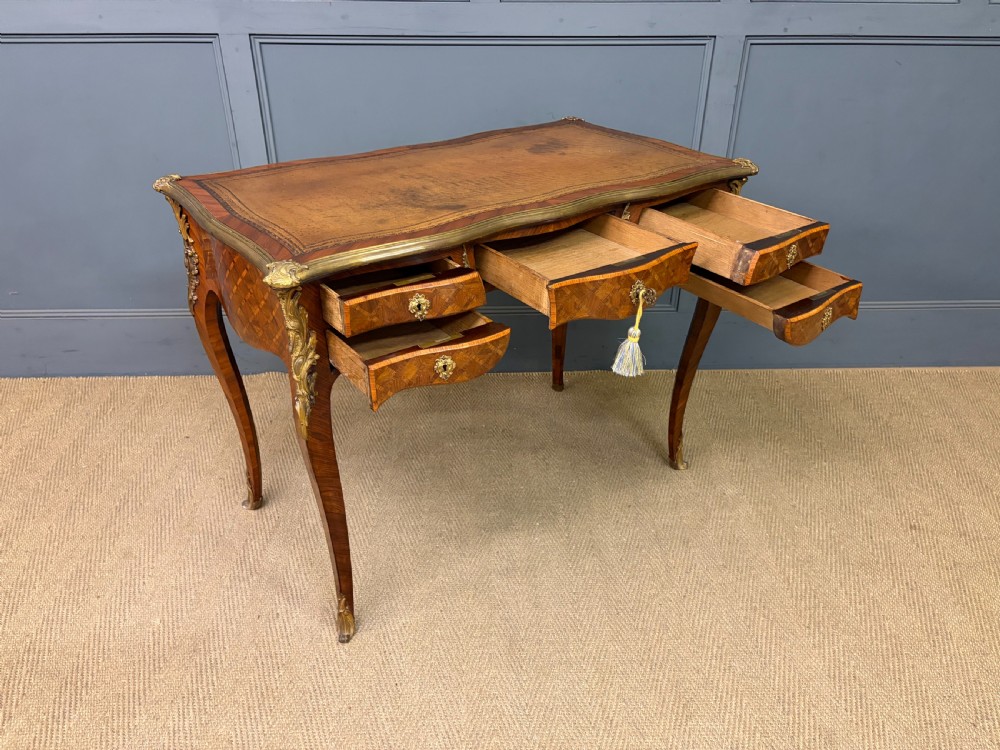 A 19th-century French Louis XV style writing desk with geometric parquetry veneers, gilt-bronze mounts, cabriole legs, and a warm brown leather writing surface. View XVII