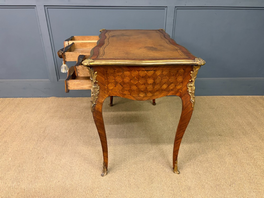 A 19th-century French Louis XV style writing desk with geometric parquetry veneers, gilt-bronze mounts, cabriole legs, and a warm brown leather writing surface. View XX