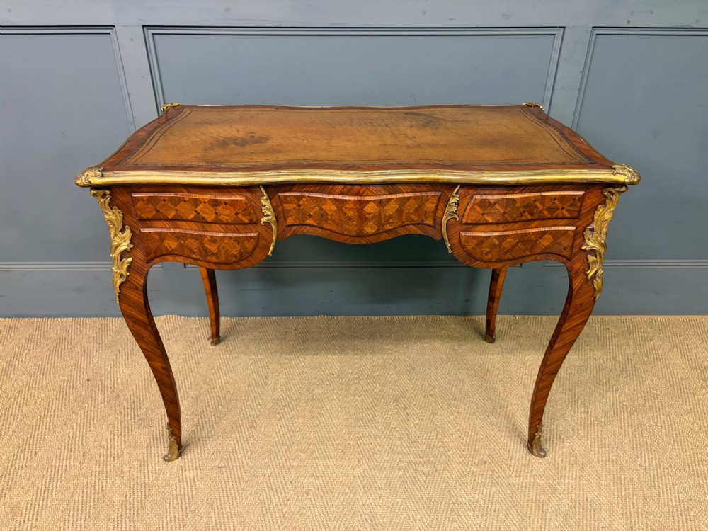 A 19th-century French Louis XV style writing desk with geometric parquetry veneers, gilt-bronze mounts, cabriole legs, and a warm brown leather writing surface. View XXI