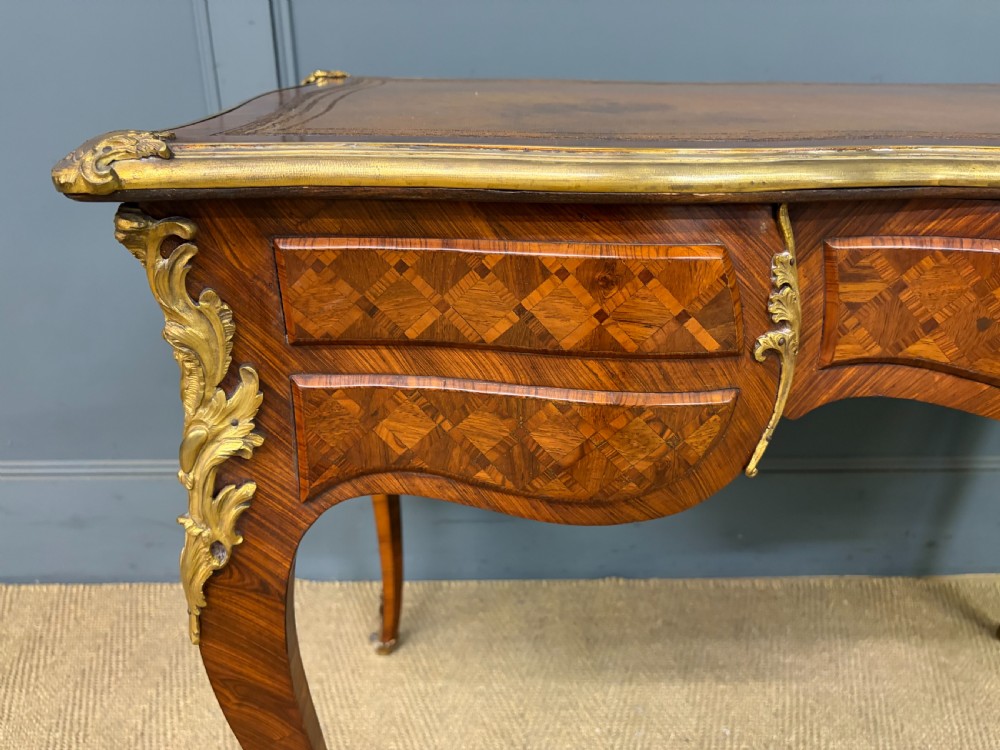 A 19th-century French Louis XV style writing desk with geometric parquetry veneers, gilt-bronze mounts, cabriole legs, and a warm brown leather writing surface. View XXII